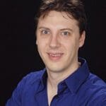 A man in blue shirt smiling for the camera.