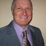 A man in a suit and tie smiling for the camera.