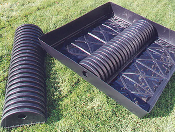 A black plastic tube laying on top of grass.